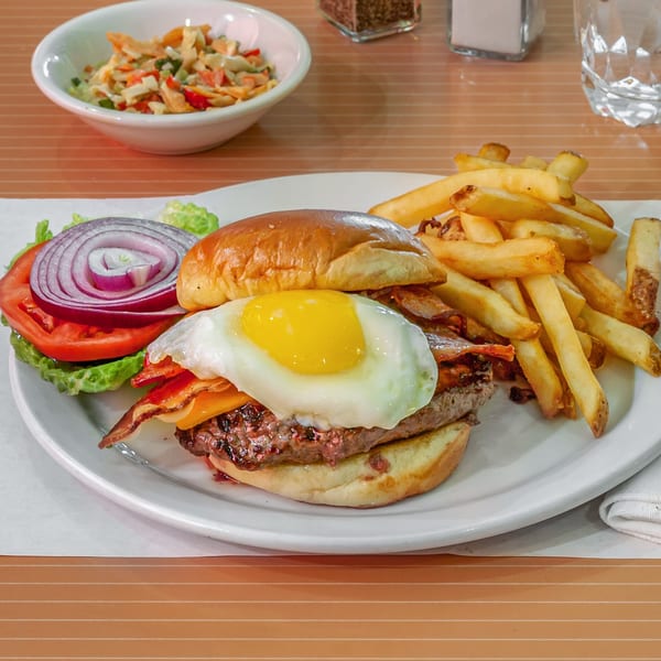 A Breakfast Club and Grill burger with a fried egg, bacon, cheese, and fries.