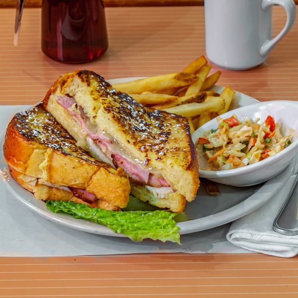 Monte Cristo sandwich with fries and coleslaw, served with syrup and coffee.